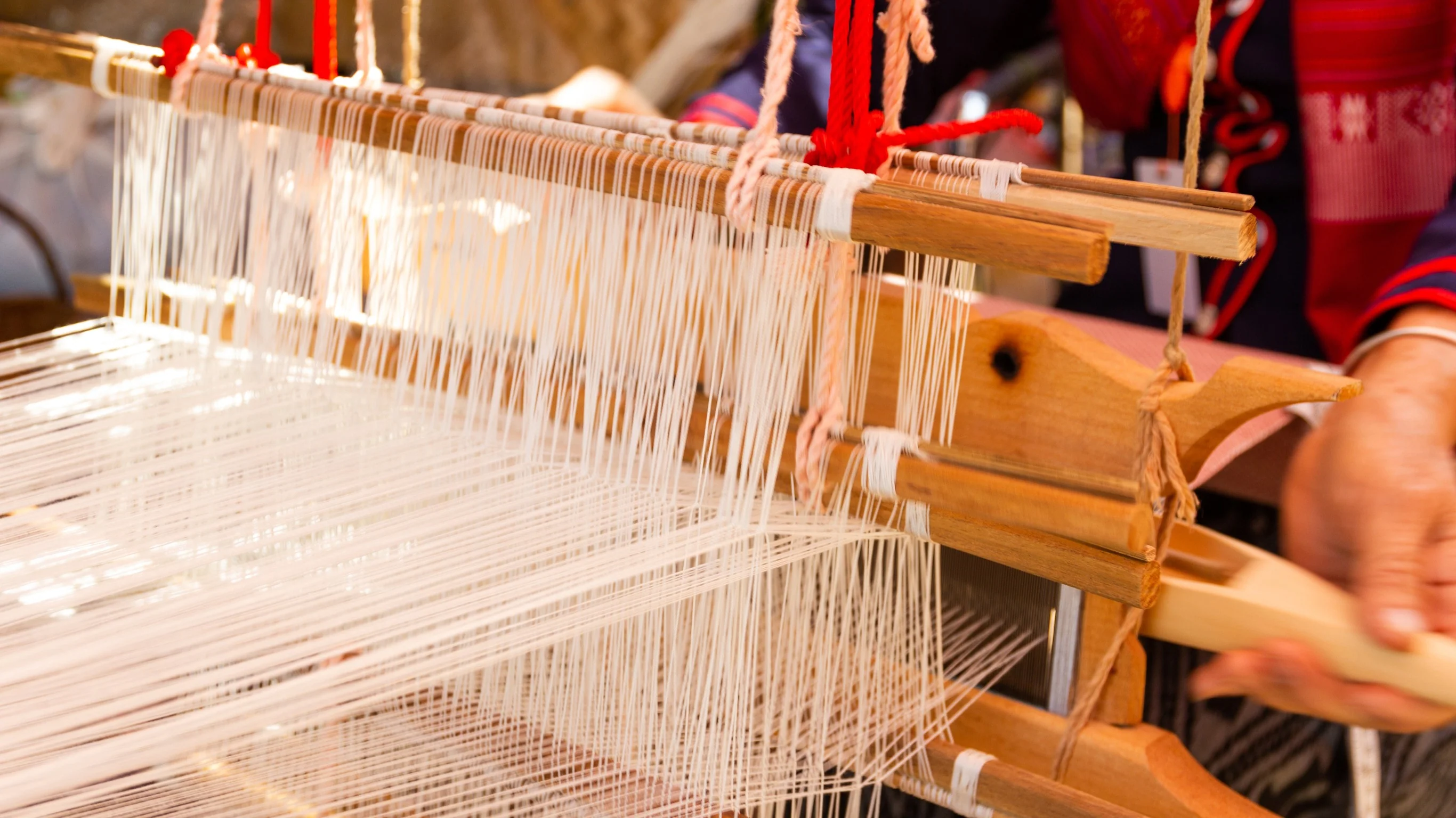 Close-up of Vietnamese silk loom showing hundreds of white silk threads arranged on traditional wooden weaving frame